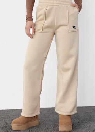 Жіночі штани широкі  на флісі теплі  трикотажні зимові з накладними кишенями 3-нитка бежевий колір s m l