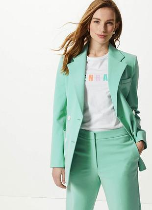 Стильний двобортний піджак мʼятного кольору з білими ґудзиками з накладними кишенями