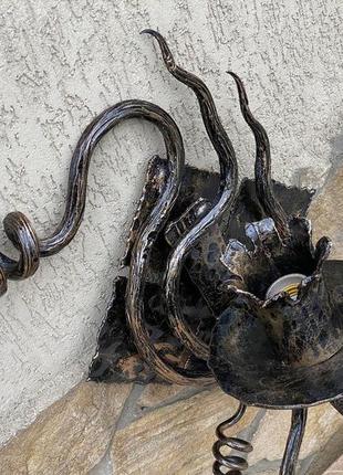 Ковані бра ручної роботи на фоні медивної лампи