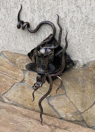 Ковані бра ручної роботи на фоні медивної лампи