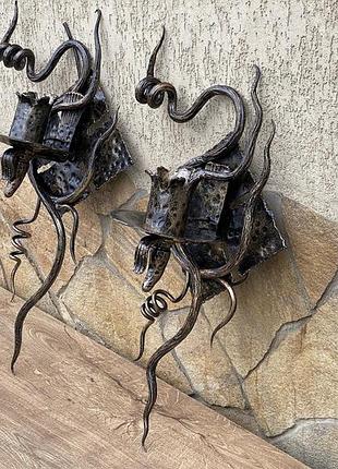 Ковані бра ручної роботи на фоні медивної лампи