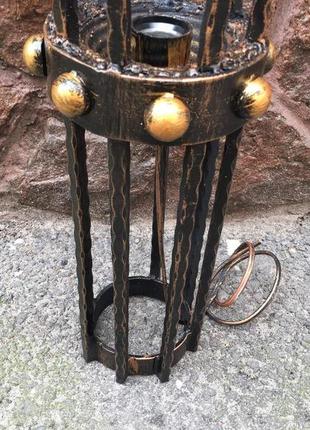 Кованый средневековый бра ручной работы на фоне средневекового фонаря (факела)