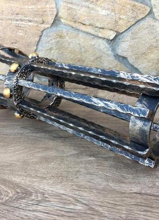 Кованый средневековый бра ручной работы на фоне средневекового фонаря (факела)