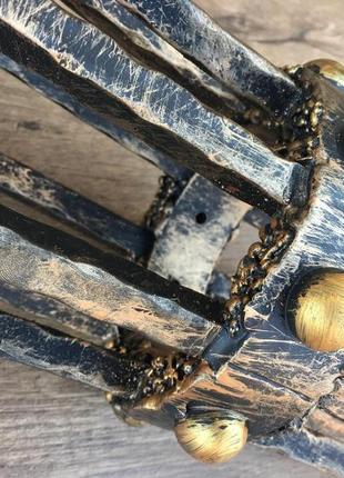 Кованый средневековый бра ручной работы на фоне средневекового фонаря (факела)