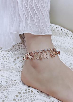 Золотистий браслет на ніжку з камінцями та підвісками метеликами