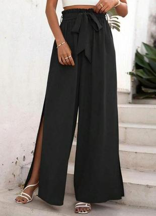 Стильные женские черные брюки на поясе свободного кроя с разрезами на ногах и карманами