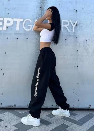 Чорні штани джогери на високій посадці вільного крою з якісної тканини з написом збоку стильні трендові