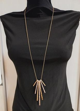 Длинная цепочка с подвесками золотистого и серебристого цвета.