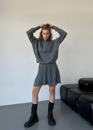 Трикотажный костюм представлен с плиссированной юбкой и лонгсливом