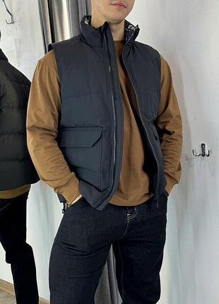 Пухова жилетка із накладними кишенями