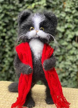 Большой пушистый черный кот в красном вязанном шарфе