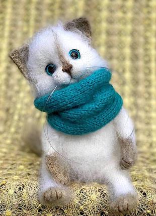 Белая пушистая зимняя кошечка в наушниках и снуде