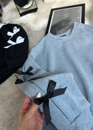Трендовый свитшот с бантиками на рукавах.
