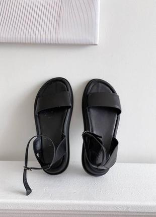 Чорні лаконічні шкіряні  босоніжки на чорній підошві з устілкою чорного кольору
ширина переднього ремінця: 4 см платформа: 2-4 см
на середню ніжку