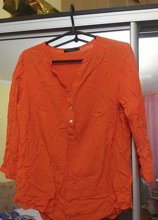 Легкая блузка оранжевого цвета с пуговицами.