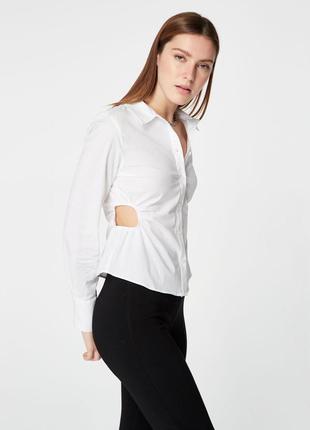 Біла сорочка на ґудзиках з вирізами з боку, які оздоблені резинкою