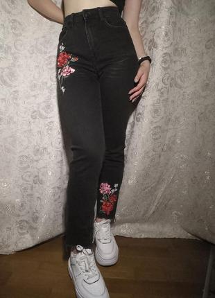 Чорні джинси з квітковими нашивками.