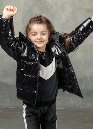 Демисезонная детская куртка черного цвета из лаковой плащевки и нашивкой1 фото