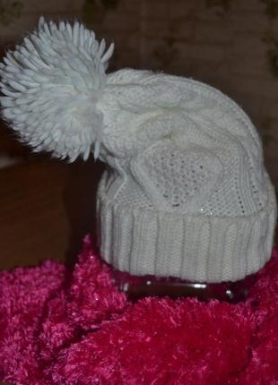 Трендовая шапочка  бренда о'stin беленькая с вязаными косами и пушистым бубоном1 фото