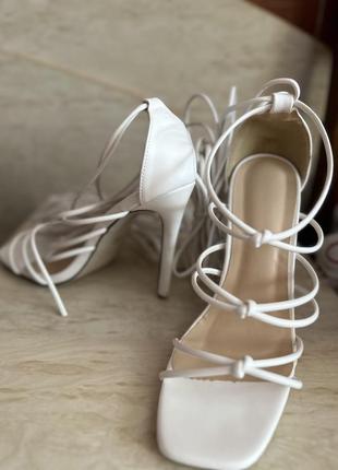 Белые босоножки на шнуровке и высоком каблуке.1 фото