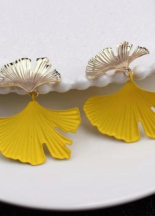 Жіночі яскраві сережки жовтого кольору з золотистими елементами в квітковій тематиці
