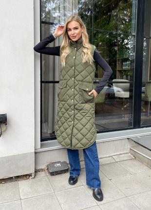 Жилетка удлиненная стеганная на кнопках воротник стойка накладные карманы с клапаном по бокам разрезы низ заокруглен ткань плащевка эмми силикон 200