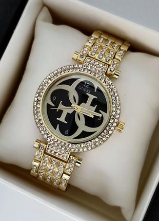 Золотистий жіночий годинник з чорним циферблатом, багато камінчиків на корпусі