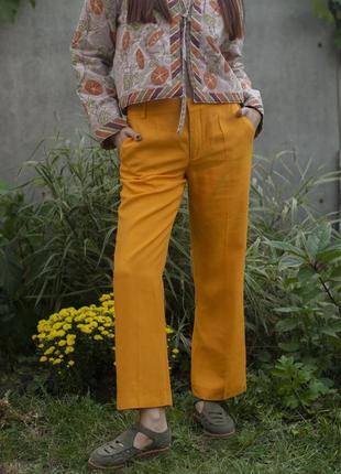 Яскраві помаранчеві брюки на невисоку дівчину.