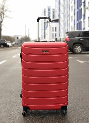 Чемодан из противоударного пластика большой красного цвета.