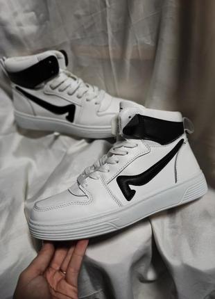 Кросівки хайтопи, високі, білого кольору з чорними вставками.