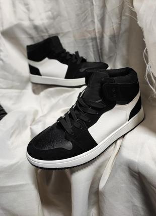 Кросівки хайтопи, високі, білого кольору з чорними вставками.