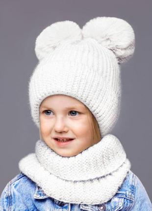 Теплый набор для девочки 5 6 7 8 лет: белая зимняя детская шапка с двумя помпонами + снуд хомут5 фото