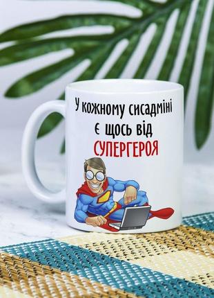 Біла чашка на подарунок з написом "у кожному сісадміні є щось від супергероя" 330 мл