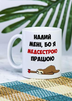 Біла чашка на подарунок з написом "налий мені, бо я медсестрою працюю" 330 мл