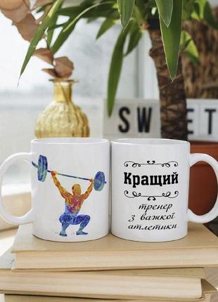 Біла чашка на подарунок з написом "кращий тренер з важкої атлетики" 330 мл