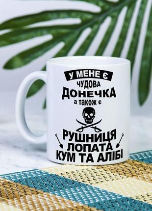 Біла чашка на подарунок з написом  "у мене є чудова дочка, кум, лопата та алібі" 330 мл