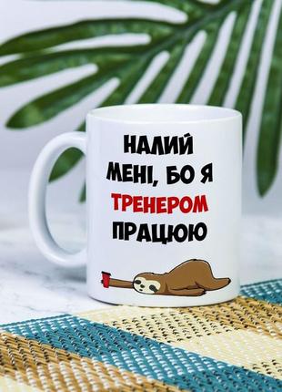 Біла чашка на подарунок з написом "налий мені, бо я тренером працюю" 330 мл