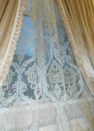 Бежеві оксамитові штори з бахромою.