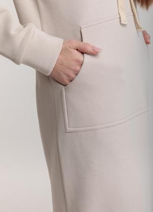 Длинное трикотажное прямое теплое платье бежевого цвета с разрезами, капюшоном и карманом7 фото