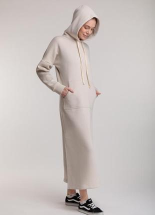 Довга пряма трикотажна тепла сукня бежевого кольору з розрізами, капюшоном і кишенею