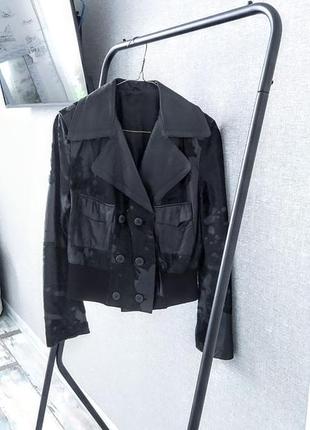 Шкіряна коротка чорна куртка зі вставками коров'ячого хутра.