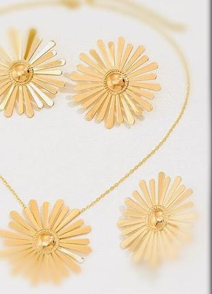 Комплект прикрас золотого кольору у формі великіх квітів: сережки, ланцюжок з кулоном та каблучка.2 фото