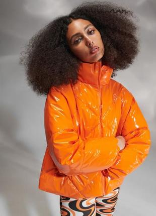 Стильная яркая лакированная дутая куртка помараенчевого цвета