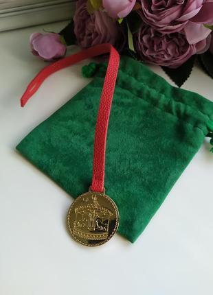 Золота червона підвіска брелок на сумку estée lauder емблема
