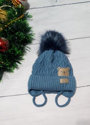 Шапка в'язана на плюшевій підкладці, з помпоном, на зав'язках