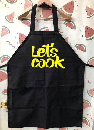 Фа000269	черный кухонный фартук с желтой надписью "lets cook"