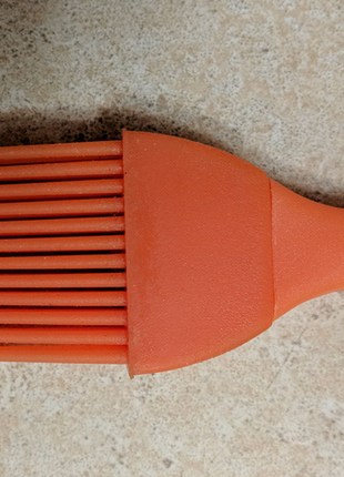 Новая оранжевая кухонная силиконовая щеточка.