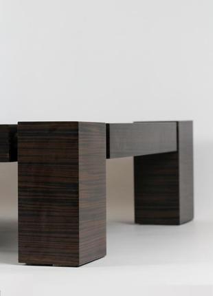 Дизайнерський журнальний столик з дерева зі скляною стільницею.