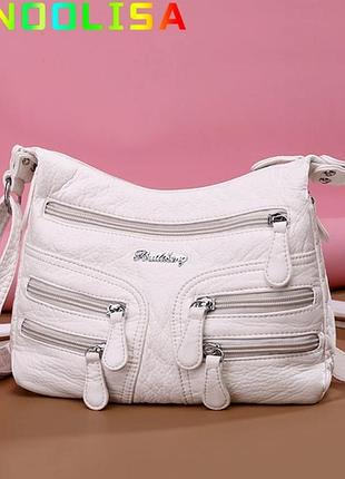 Біла жіноча сумочка з кишенями.