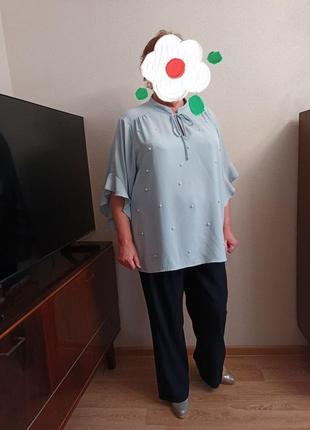 Блуза голубого цвета с жемчугом большого размера.